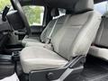Interior view of a 2017 Ford F-250 showing front seats with light grey fabric upholstery and a console with cup holders