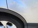 Close-up of the wheel and tire of a 2015 Ford Escape showing minor scratches on the fender and wheel arch