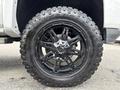 A close-up of a black off-road tire mounted on a wheel with a multi-spoke design showcasing the tread pattern and brand name Wrangler