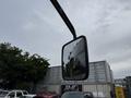 A side mirror of a 2018 Grande West Vicinity bus reflecting nearby trees and structures