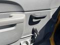 A close-up view of the door panel of a 2013 Chevrolet Silverado 1500 featuring a handle a control knob and a cup holder area