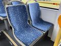 Two empty blue bus seats with a patterned fabric located in a public transport vehicle