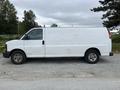 A 2014 GMC Savana van in white with a plain exterior and side doors visible, parked on a gravel surface