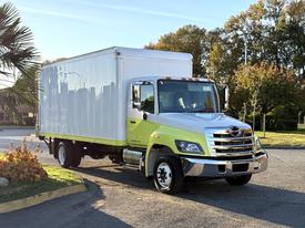 A 2018 Hino 268 truck with a bright green and white box body parked at an angle showing its front and side view