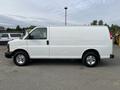 A white 2012 GMC Savana van is parked with a smooth surface and chrome wheels. The van features a simple design with large side doors and no windows on the passenger side