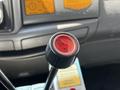 Close-up of a red lift button on the gear shift of a 2009 Ford LCF 550 with a black handle and surrounding controls in the foreground