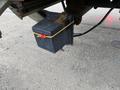 A black battery box secured with a yellow strap hanging from the undercarriage of a 2014 International Durastar truck