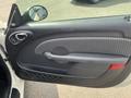 Interior door panel of a 2005 Chrysler PT Cruiser featuring a handle and speaker with a textured grip and red accent near the bottom