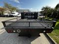A 2016 Ford F-550 truck with a flatbed and metal mesh sides is parked, showcasing its rear view and taillights