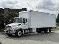 A white 2017 Hino 338 box truck parked with a large cargo area and a front cab featuring headlights and a grille