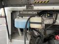 A close-up view of the engine compartment of a 2012 Workhorse W62 showing two fluid reservoirs one blue and one clear located near engine components