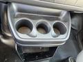 A black plastic cup holder compartment with three circular sections for cups located in a vehicle's interior