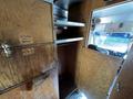 Interior view of a 2009 Morgan Olson Workhorse showing wooden cabinetry with shelves and a hinged door open revealing storage space