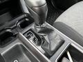 The gear shift of a 2022 Toyota Tacoma featuring a black leather boot and adjacent cup holders