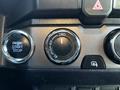 A close-up view of the dashboard of a 2021 Toyota Tacoma showing the engine start stop button the four-wheel drive control and other dashboard controls