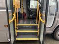 The entrance of a 2017 Chevrolet Express showing yellow steps and handrails leading to the driver's seat and interior of the vehicle