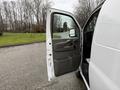 A white 2009 Chevrolet Express van with the driver's side door open showing the interior and control panel