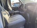 Interior view of a 2012 GMC Savana showing two front seats with gray fabric upholstery and a dashboard with various controls and compartments