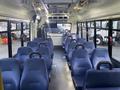 Interior view of a 2017 Chevrolet Express showing rows of blue upholstered seats and handrails with empty space in the aisle