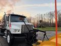 A 2006 Freightliner M2 106 snow plow truck with a large yellow plow attached at the front and a mounted light bar on the cab