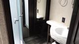 A modern bathroom featuring a sink with a marble countertop a mirror and a glass shower door in a recreational vehicle