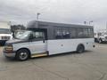 A 2017 Chevrolet Express shuttle bus with a gray and white exterior and large windows parked on a lot