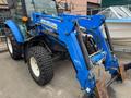 A blue 2016 New Holland T475 tractor with a front loader attachment and large tires parked beside a boat