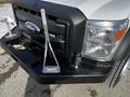 A 2011 Ford F-450 Super Duty with a black grille and chrome accents featuring a visible tow hook and an antenna on the front fender