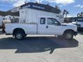 White 2013 Ford F-250 SD pickup truck with a standard cab and flatbed visible from the side