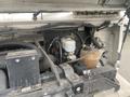 Close-up of the engine compartment of a 2012 Ford Econoline showing various components including the cooling system reservoir and electrical wiring
