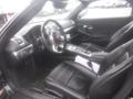 Interior of a 2016 Porsche Boxster featuring black leather seats a central console and a steering wheel with the Porsche logo