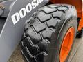 Close-up of a large tire on a 2018 Doosan DL300 -5 with a rugged tread pattern and an orange rim