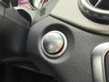 Close-up of a button on the dashboard of a 2016 Mercedes-Benz GLA-250 featuring a circular design with a symbol that resembles a car with a key inside an outline