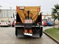 A 2012 International WorkStar truck with a large orange salt spreader attached at the back displaying a caution sign that reads KEEP BACK 20 METERS