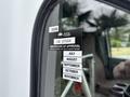 A side view of a white 2014 Ford E-350 van featuring a sticker on the window indicating a certificate of approval with various month labels
