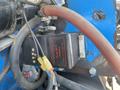 A close-up view of a controller labeled Model STP Mounted on machinery with various wires and hoses connected to it