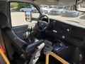 A 2017 Chevrolet Express interior featuring a steering wheel with controls dashboard with gauges and a driver's seat with a handrail