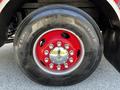 Close-up of a wheel from a 2006 Emergency One Fire Truck featuring a large black tire with a red rim and chrome hubcap with multiple bolts