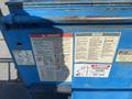 A blue 1997 Genie S-65 4X4 lift with warning and notice labels prominently displayed on its side