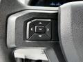 A close-up view of a steering wheel control panel featuring directional buttons and an "OK" button