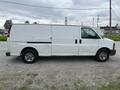 A white 2014 GMC Savana van is parked on gravel showing a side view with no windows on the cargo area