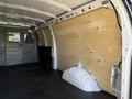 Interior view of a 2017 GMC Savana cargo van with a wooden panel lining the sides and a partially exposed wheel well in the floor