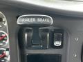 A close-up view of a trailer brake handle in a 2010 Freightliner M2 106 truck's interior featuring labeled controls in a dark panel