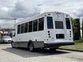 A white and gray 2020 Chevrolet Express shuttle bus with large windows and a rear door parked at an angle