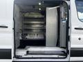 A 2017 Ford Transit van with the rear doors open showing metal shelving installed inside to organize tools and equipment