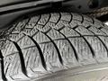 Close-up of a rugged tire tread featuring deep grooves and metal studs designed for enhanced traction on snow and ice