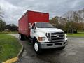 A white 2008 Ford F-750 truck with a red cargo box parked on a road