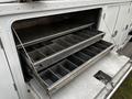 A 2016 Ford F-550 with a rear storage compartment featuring multiple metal trays arranged in a stacked configuration