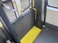 A 2017 Chevrolet Express with a wheelchair ramp folded down in the foreground featuring a textured surface and a bright yellow platform