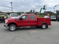 A red 2011 Ford F-250 SD pickup truck with a utility bed and tool compartments on the side parked in a commercial lot